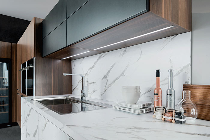 Vue zoomée de la cuisine Arcos Edition avec le plan de travail effet marbre et de l’éclairage dans le meuble haut.