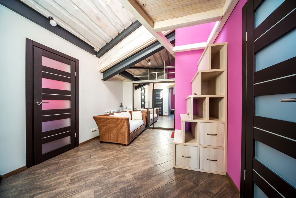 Vue d'une pièce ouverte avec un mur contrasté rose vif et une bibliothèque design.