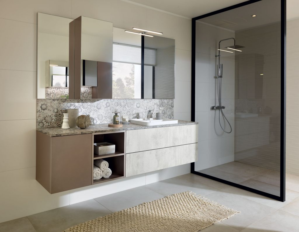 Vue de biais de la salle de bains Arcos Edition coloris gris clair marbré et Loft coloris marron clair cacao et la crédence avec le motif Mexico.