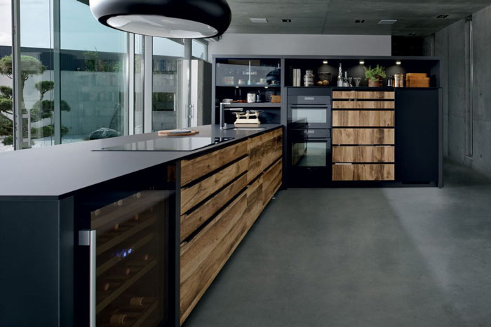Vue du linéaire qui souligne la finesse du plan de travail compact couleur noire Nano Black dans la cuisine Arcos Edition, façades coloris marron clair effet bois Murphy.