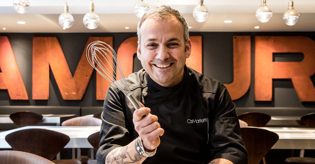 Portrait de Carl Marletti, chef pâtissier parisien, avec un fouet de cuisine.