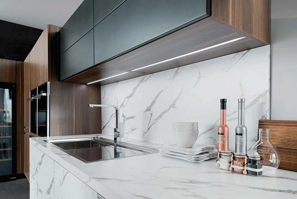 Vue zoomée de la cuisine Arcos Edition avec le plan de travail effet marbre et de l’éclairage dans le meuble haut.