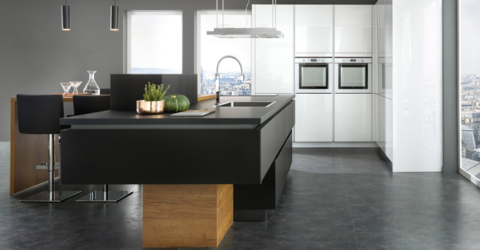 Vue d'ensemble de la cuisine sur mesure Arcos Edition en noir Nano Black face aux armoires four en blanc Glamour Vertica.