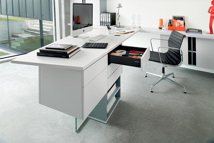 Bureau gris clair dans une pièce dédiée au télétravail, avec un chaise noire.