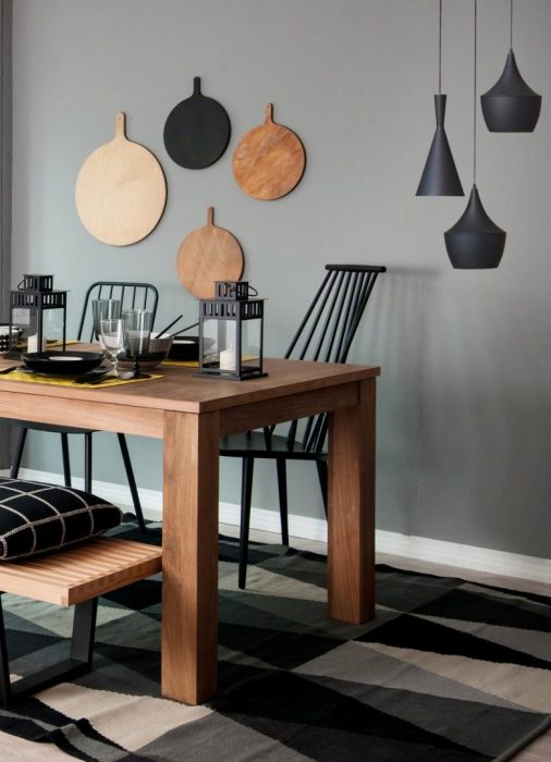 Les éléments design et cette table en bois massif sont sublimés par un mur gris vert.