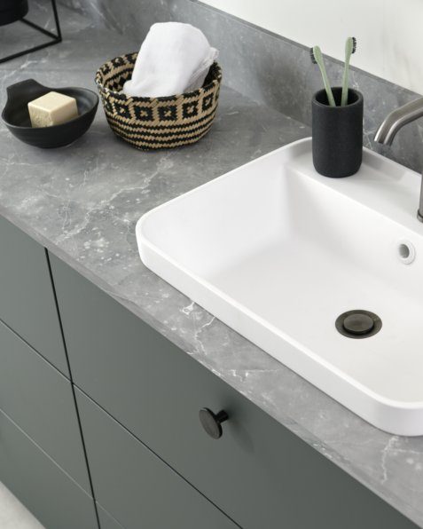 Ce plan de toilette est contrasté par le gris aspect pierre minérale et la délicatesse du vert mat.