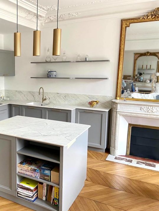 L'effet or vieilli sur le miroir et les suspensions harmonise somptueusement cette cuisine grise et quartz blanc - Réalisation magasin Schmidt Barentin.