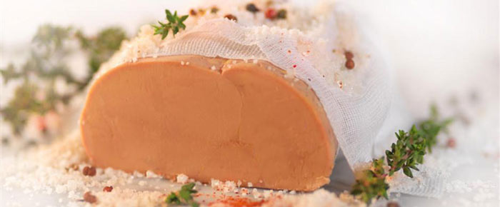 Foie gras maison couvert avec une gaze blanche et décoré avec fleur de sel, thym frais et grains de poivre.