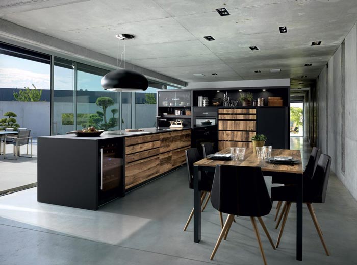 Vue d'ensemble de la cuisine design Arcos Edition avec les façades couleur marron clair effet bois et le plan de travail stratifié fin noir.