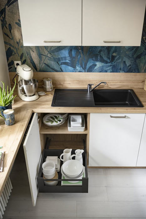 Petite cuisine en « L » fermée avec des murs en papier peint motif végétal bleu
